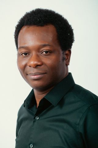 Head and shoulders portrait of Dapo Bankole in a black shirt, smiling.